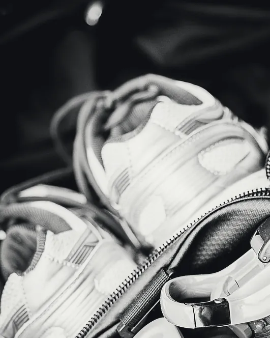 Sac de sport ouvert, chaussures blanches et gourde dedans.
