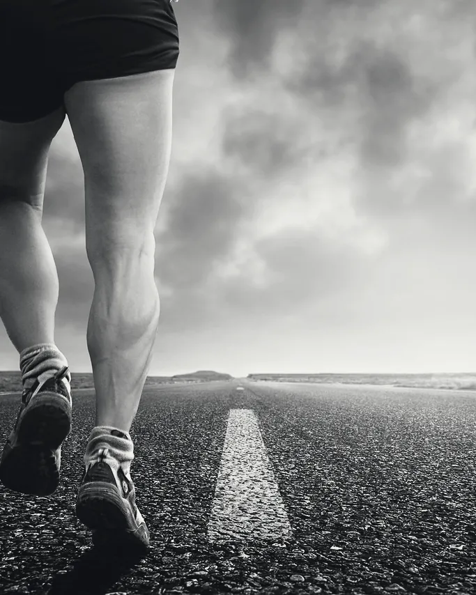 Jambes d’un coureur en short sur une route déserte.