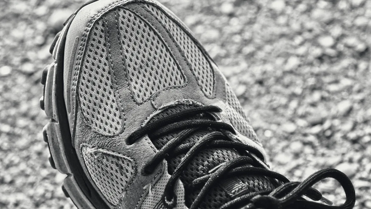 Chaussure de course posée sur le gravier, laçage en gros plan.