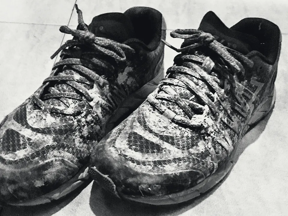 Une paire de chaussures de trail couvertes de boue sèche.